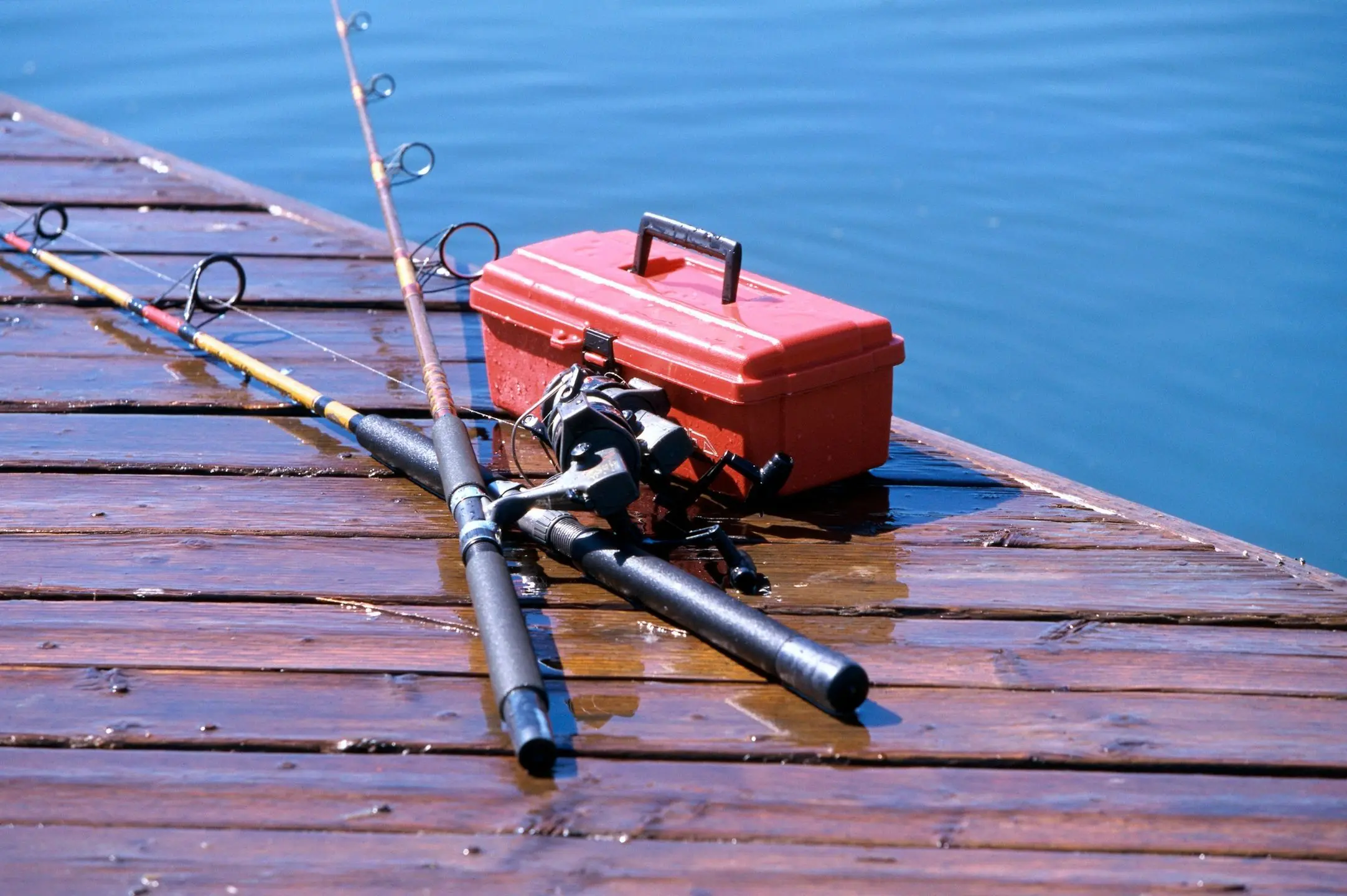 Fishing rods and red tackle box on dock