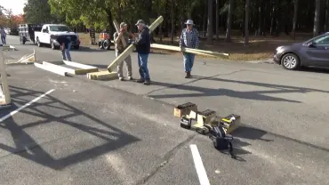 People carrying wooden beams in parking lot