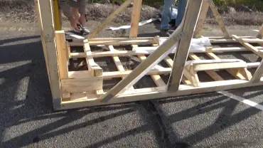 People assembling wooden framework outdoors