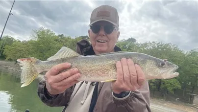 Man holding a large fish by the lake