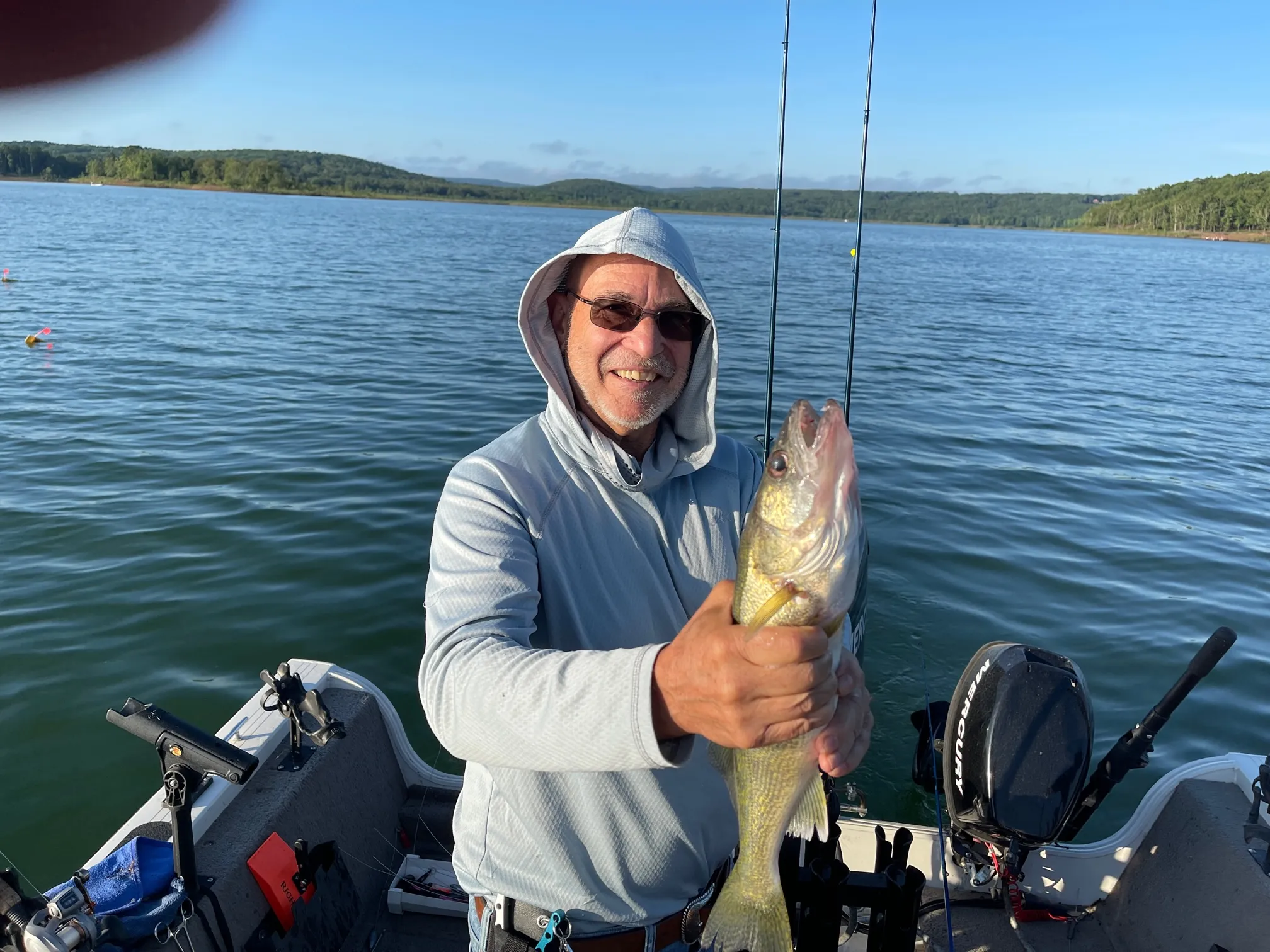 Smiling fisherman with catch on lake